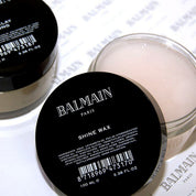 Balmain shine wax container with black lid and white body on a light background