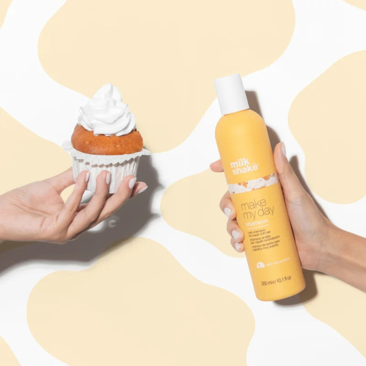 Hand holding a cupcake and a bottle of 'make my day' product on a yellow and white background