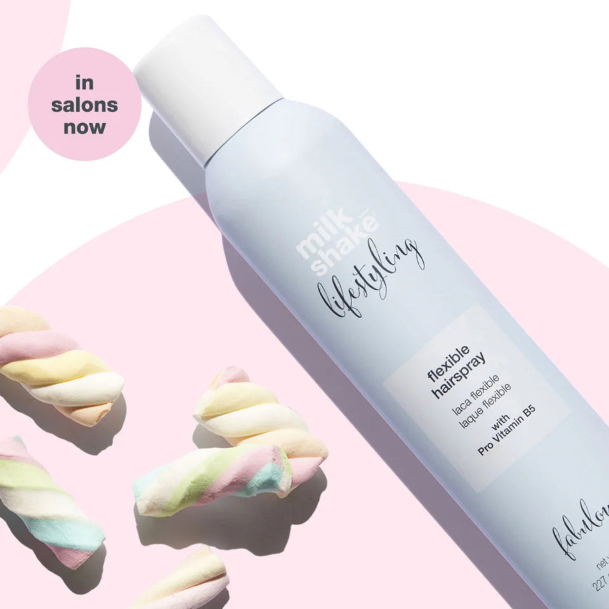 Milk Shake Hairspray bottle with colorful hair ties on a pink background