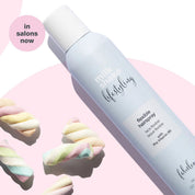 Milk Shake Hairspray bottle with colorful hair ties on a pink background
